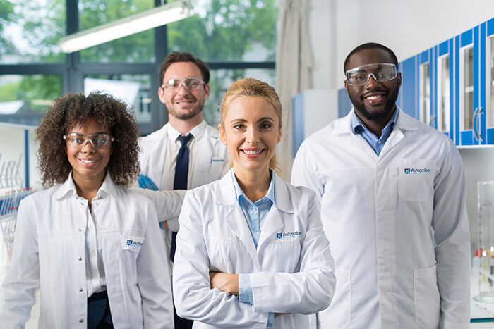 Four employees with lab coats on, with an Autoscribe Informatics logo on the lab coats.