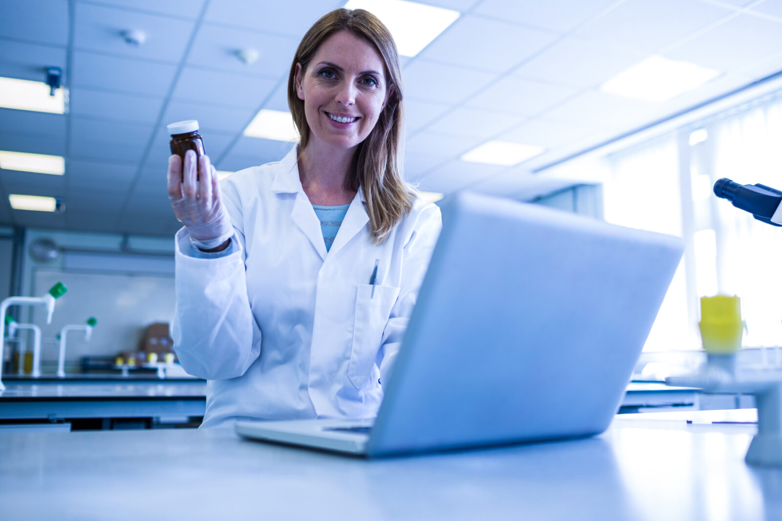 Lady in Lab in front of a computer screen holding a pot