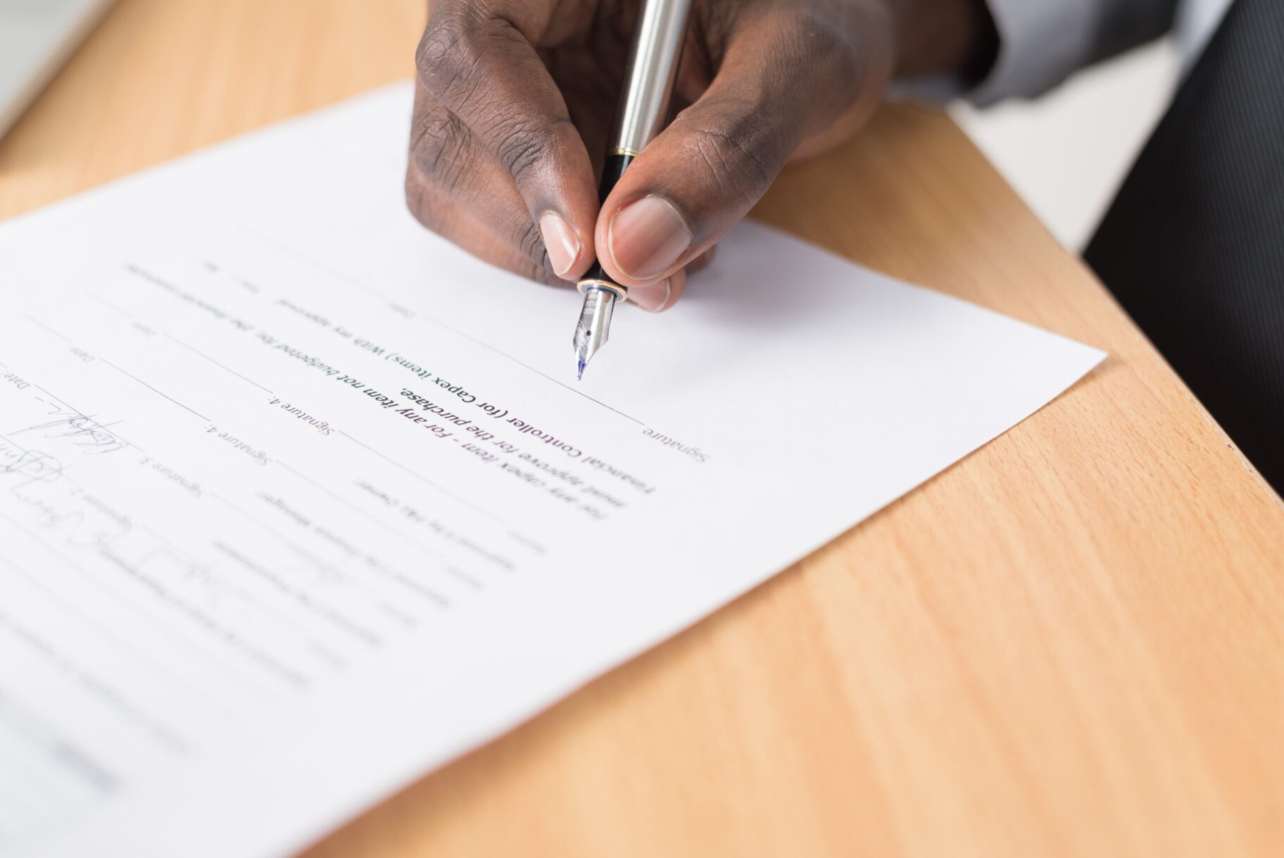 Picture of a document being signed. The final step of a formal transaction.