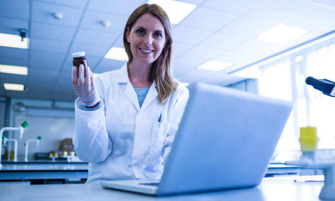 Lady in Lab in front of a computer screen holding a pot
