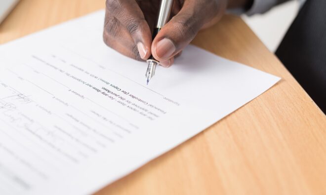 Picture of a document being signed. The final step of a formal transaction.